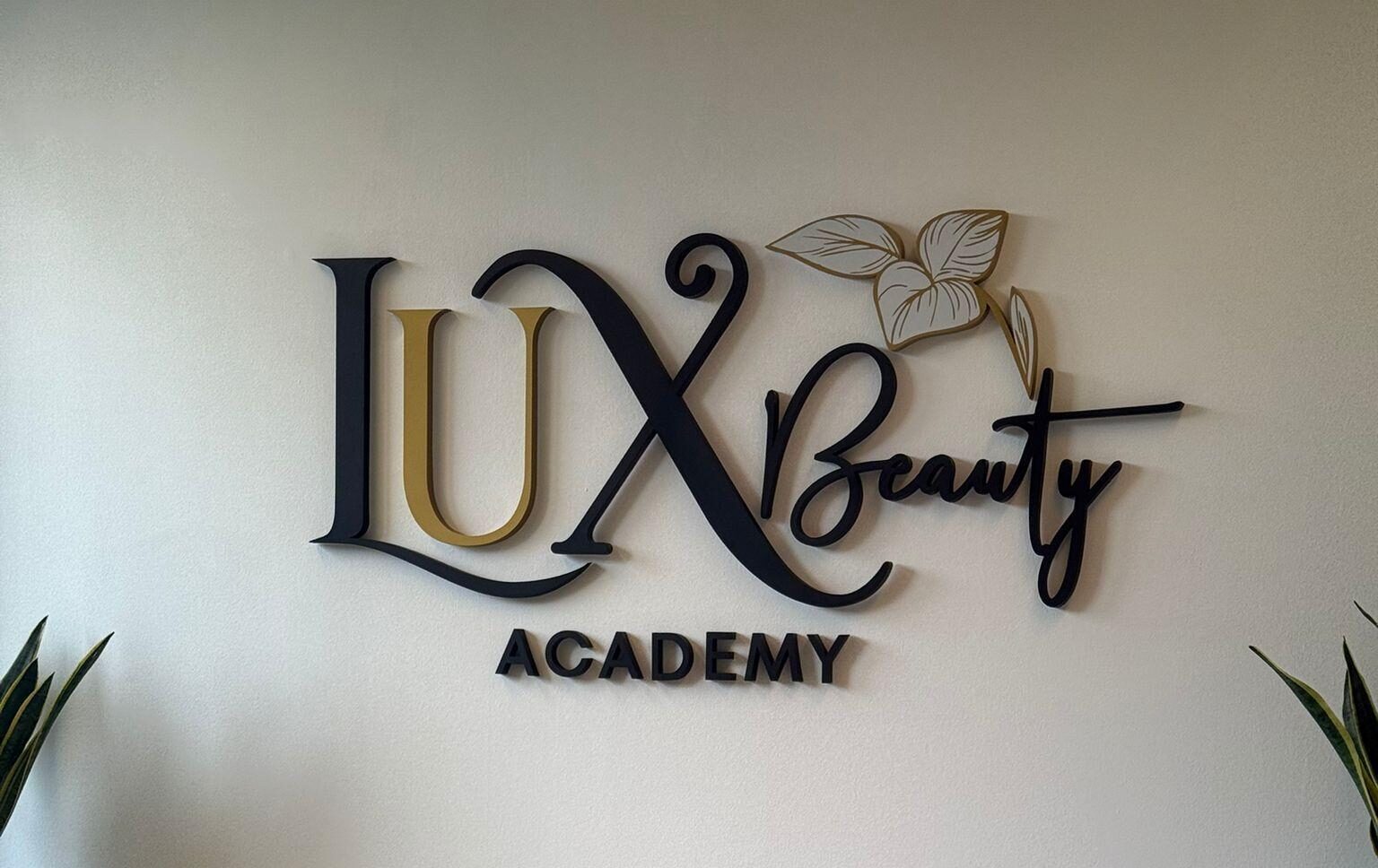 Non-illuminated interior 3D wall sign LUX Beauty Academy in black and gold acrylic letters with leaf logo