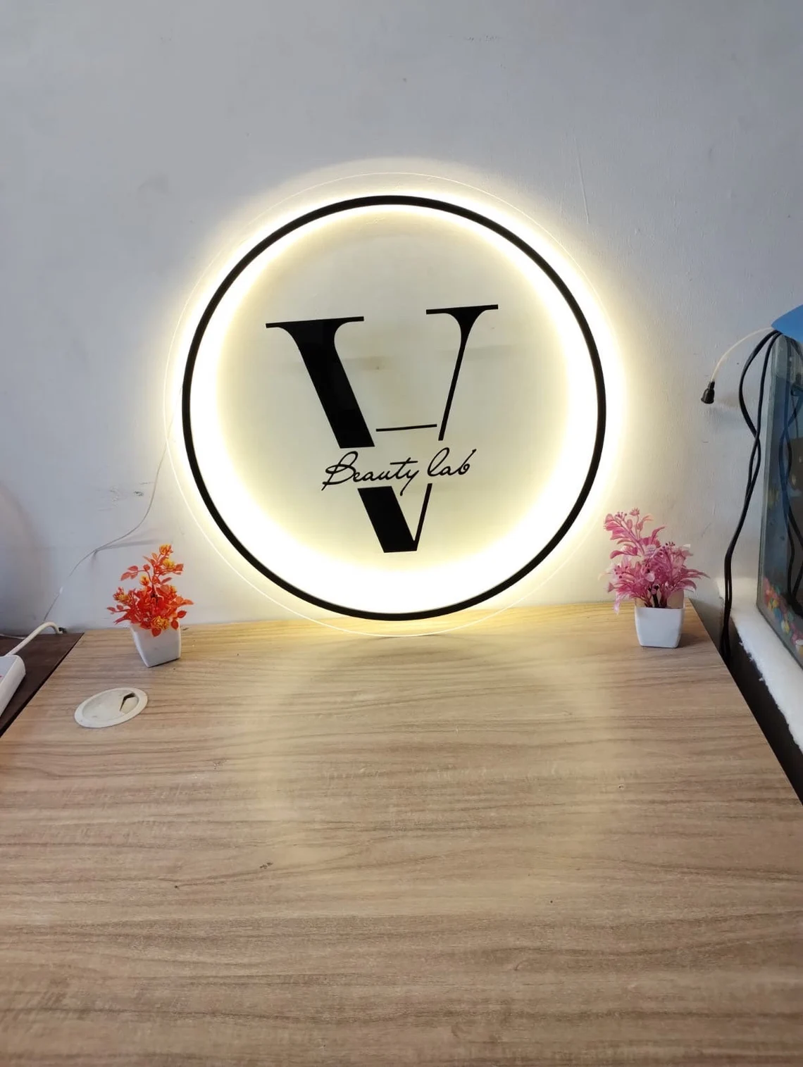 Custom acrylic logo sign with LED backlighting installed on office wall, modern illuminated signage