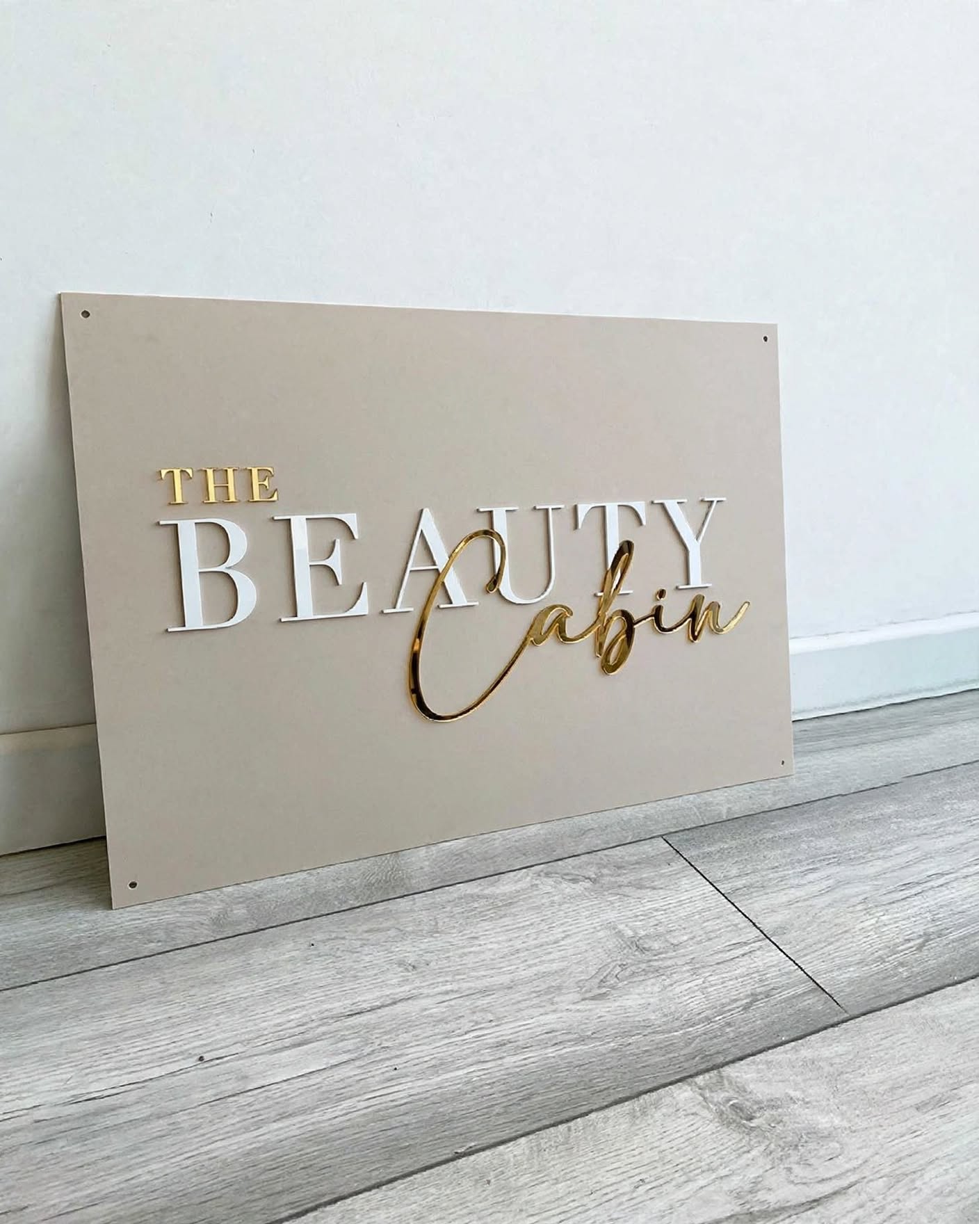 Beige panel with white 3D letters and a gold mirror script word