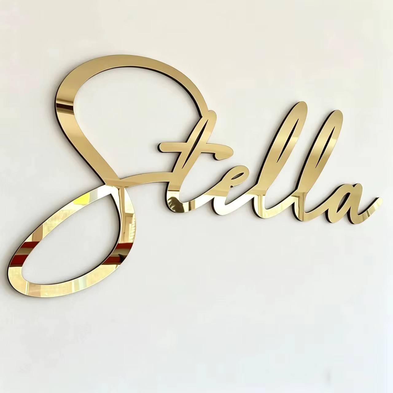 Large gold mirror acrylic script name cut from a single piece and mounted on a white wall