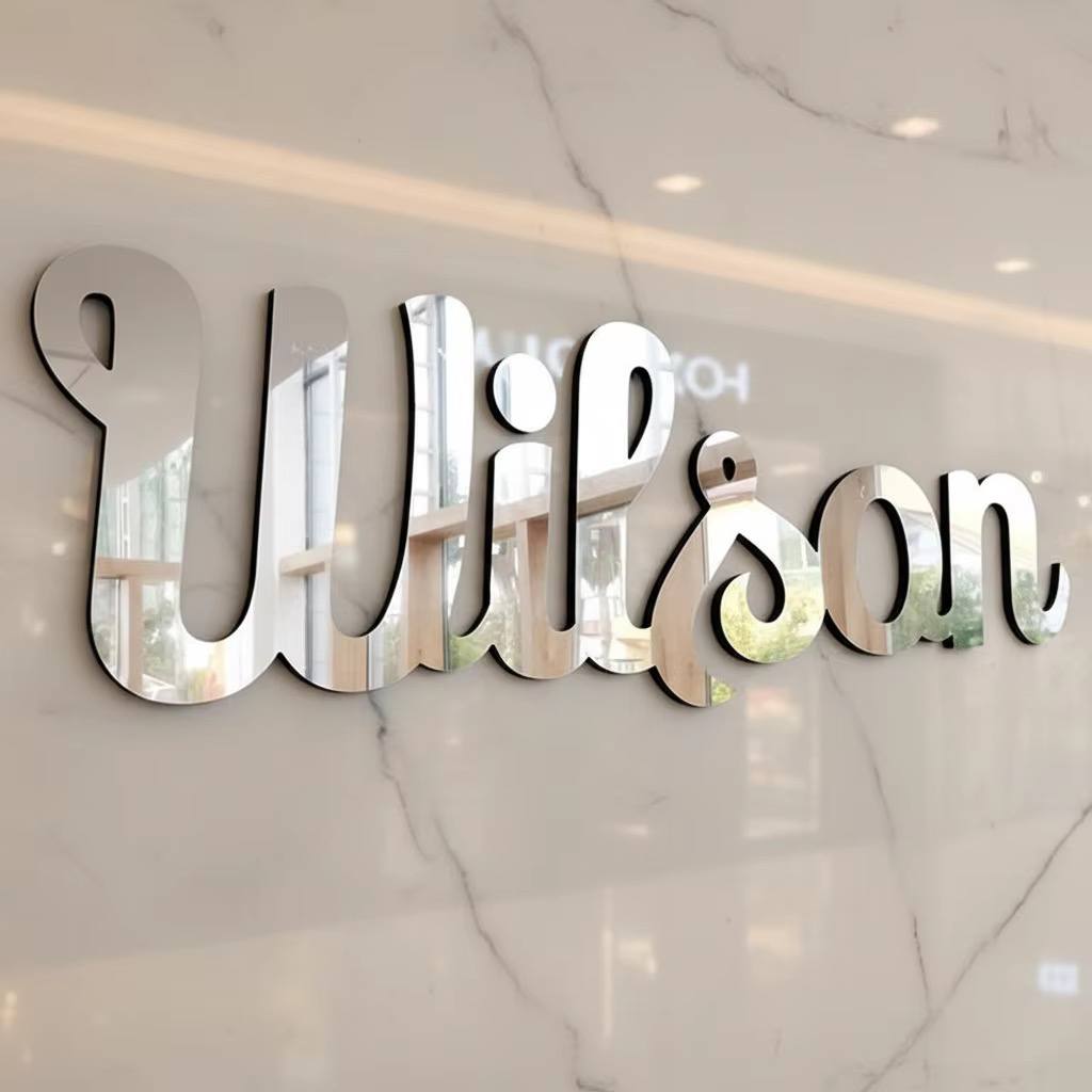 Silver mirror acrylic script name with black edge mounted on a white marble wall