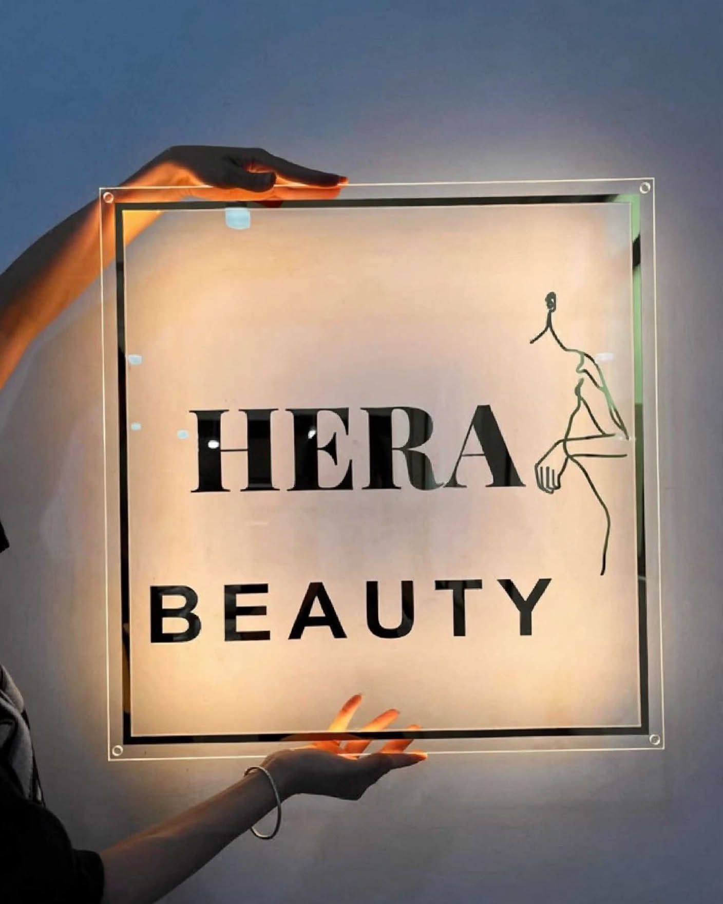 Backlit square clear acrylic sign with black mirror lettering and line-art logo