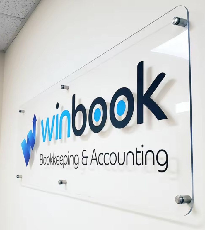 Large clear acrylic wall panel on standoffs with 3D logo and black lettering in an office